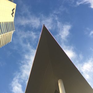 economic development cover image for epperson company's projects page with pointy building casting shadow worm's eye view looking up at sky cloudy blue sky next to the w hotel dallas texas
